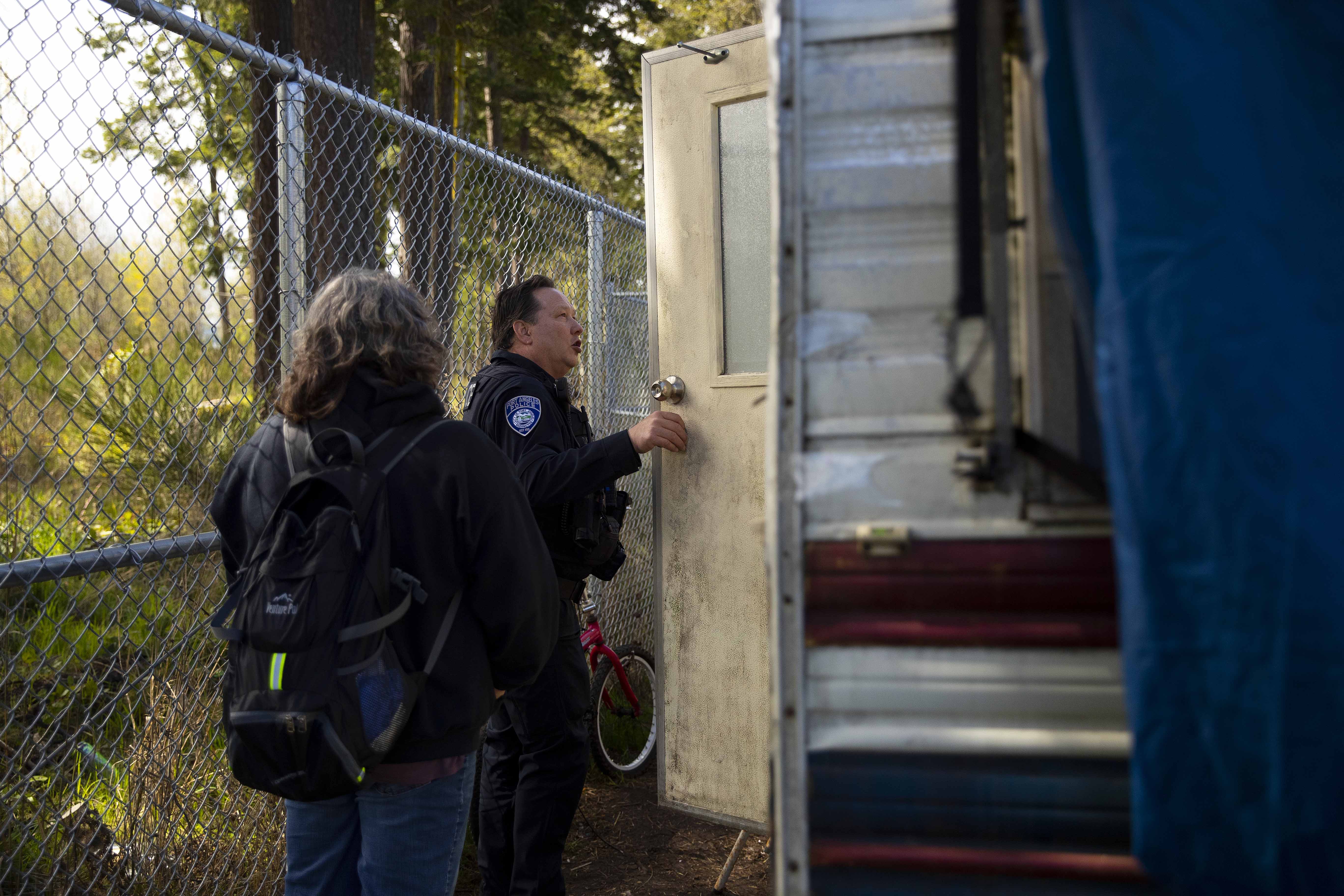 Pam Paine, outreach coordinator at Olympic Peninsula Community Clinic, left, and Port Angeles code enforcement officer Derek Miller, right, check on an individual living in an R.V. and offer shelter options and services on Tuesday, April 25, 2023, in Port Angeles. KUOW Photo/Megan Farmer.